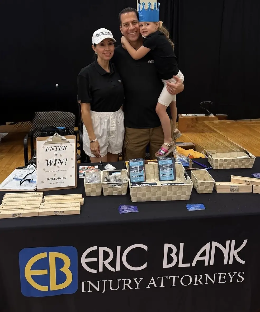 A family with a young child in a paper crown at the Eric Blank Injury Attorneys table during the East Las Vegas Back to School event