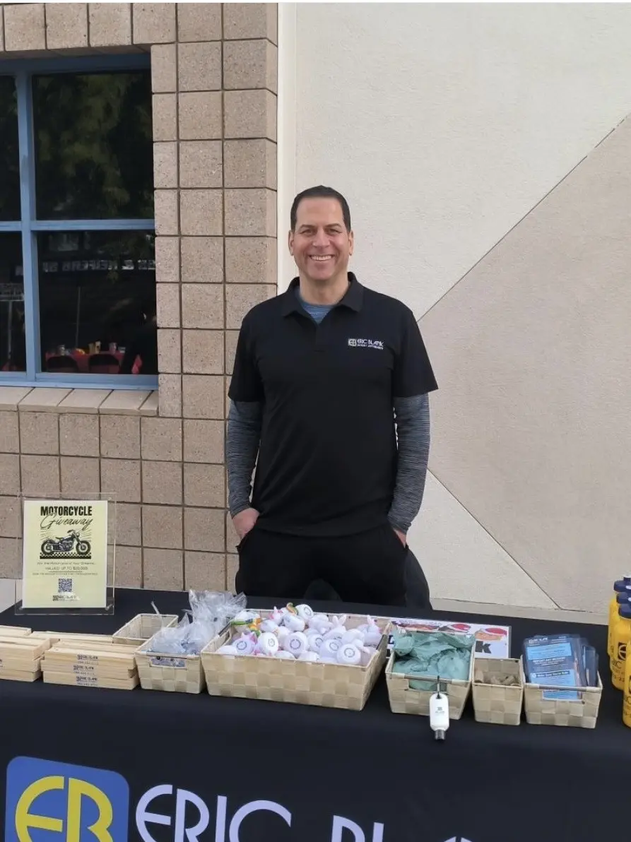 Eric Blank Injury Attorneys team member at the firm’s outdoor event table stocked with gifts and giveaways