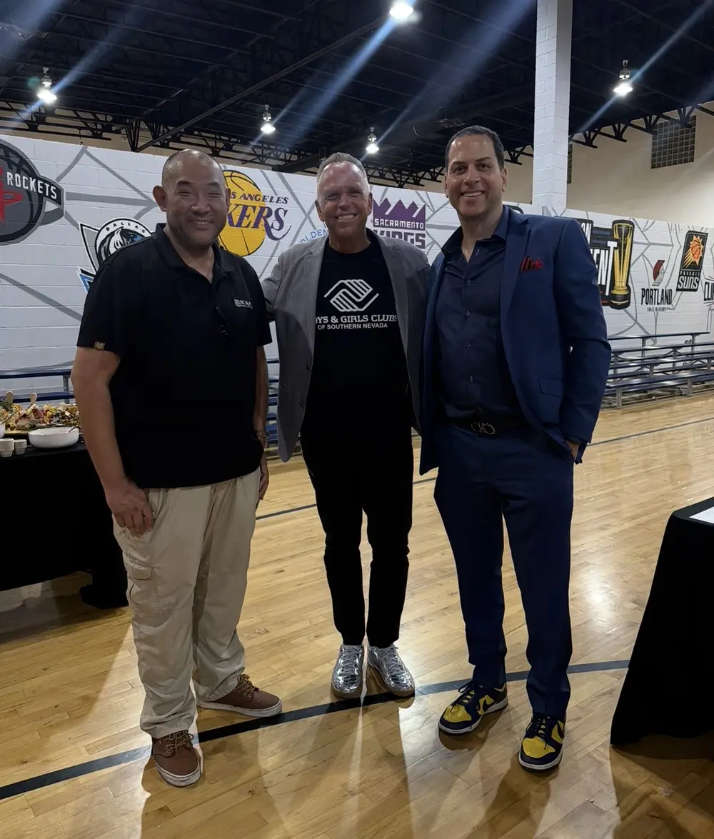 Three attendees in dress clothes and sneakers on a Boys & Girls Club gym floor at the annual Sneaker Ball